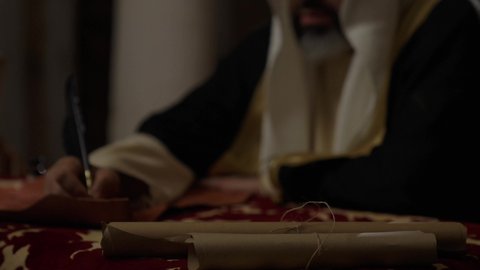 ارتداء الزي الشعبي في المناسبة الوطنية، تصوير مقرب لرجل عربي خليجي سعودي يرتدي الغترة والعقال الذهبي والبشت يمسك بيده الريشة يقوم بالكتابة على مخطوطة جلد تاريخية، الخطابات والمراسلات التراثية لتأسيس الدولة الأولى 1727م، يوم بدينا 22 فبراير، الفخر بأصالة المملكة