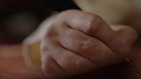 ارتداء الزي الشعبي في المناسبة الوطنية، تصوير مقرب لرجل عربي خليجي سعودي يرتدي الغترة والعقال الذهبي والبشت يمسك بيده الريشة يقوم بالكتابة على مخطوطة جلد تاريخية، الخطابات والمراسلات التراثية لتأسيس الدولة الأولى 1727م، يوم بدينا 22 فبراير، الفخر بأصالة المملكة