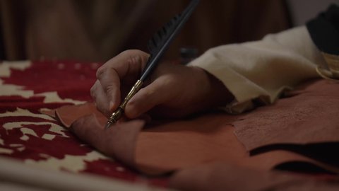 الفخر بأصالة المملكة، ارتداء الزي الشعبي في المناسبة الوطنية، تصوير مقرب لرجل عربي خليجي سعودي يرتدي الغترة والعقال الذهبي والبشت يمسك بيده الريشة يقوم بالكتابة على مخطوطة جلد تاريخية، الخطابات والمراسلات التراثية لتأسيس الدولة الأولى 1727م، يوم بدينا 22 فبراير