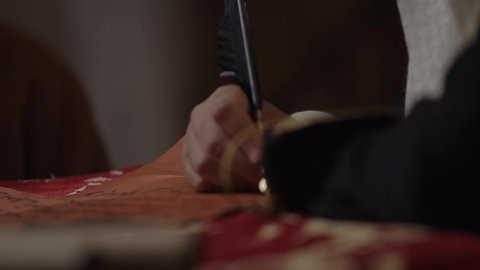 يوم بدينا 22 فبراير، الفخر بأصالة المملكة، ارتداء الزي الشعبي في المناسبة الوطنية، تصوير مقرب لرجل عربي خليجي سعودي يرتدي الغترة والعقال الذهبي والبشت يمسك بيده الريشة يقوم بالكتابة على مخطوطة جلد تاريخية، الخطابات والمراسلات التراثية لتأسيس الدولة الأولى 1727م