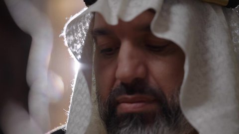 يوم بدينا 22 فبراير، الفخر بأصالة المملكة، ارتداء الزي الشعبي في المناسبة الوطنية، تصوير مقرب لرجل عربي خليجي سعودي يرتدي الغترة والعقال الذهبي والبشت يمسك بيده الريشة يقوم بالكتابة على مخطوطة جلد تاريخية، الخطابات والمراسلات التراثية لتأسيس الدولة الأولى 1727م