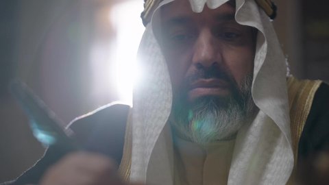 يوم بدينا 22 فبراير، الفخر بأصالة المملكة، ارتداء الزي الشعبي في المناسبة الوطنية، تصوير مقرب لرجل عربي خليجي سعودي يرتدي الغترة والعقال الذهبي والبشت يمسك بيده الريشة يقوم بالكتابة على مخطوطة جلد تاريخية، الخطابات والمراسلات التراثية لتأسيس الدولة الأولى 1727م