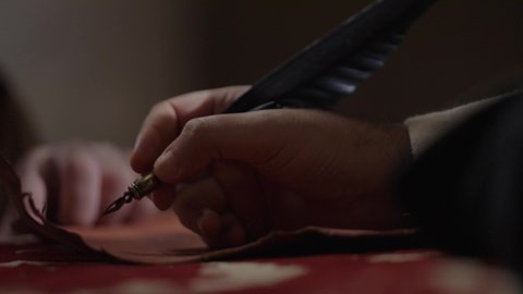 الفخر بأصالة المملكة، ارتداء الزي الشعبي في المناسبة الوطنية، تصوير مقرب لرجل عربي خليجي سعودي يرتدي الغترة والعقال الذهبي والبشت يمسك بيده الريشة يقوم بالكتابة على مخطوطة جلد تاريخية، الخطابات والمراسلات التراثية لتأسيس الدولة الأولى 1727م، يوم بدينا 22 فبراير