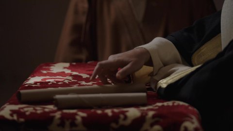 الخطابات والمراسلات التراثية لتأسيس الدولة السعودية الأولى 1727م، يوم بدينا 22 فبراير, ارتداء الزي الشعبي في المناسبة الوطنية، الفخر بأصالة المملكة، تصوير مقرب لرجل عربي خليجي سعودي يرتدي الغترة والعقال الذهبي والبشت يقوم بتسليم مخطوطة جلد تاريخية إلى شخص آخر