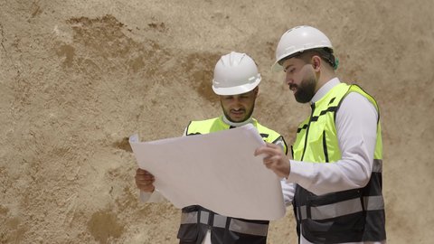 مهندسان عربيان خليجيان سعوديان يرتديان السترة وخوذة الحماية يقفان على اطلال قصر سلوى في البجيري الدرعية، يوم بدينا 1727 م، ذكرى تأسيس الدولة السعودية الأولى 22 فبراير، دراسة فن العمارة القديم واساسيات بناء البيوت الطينية