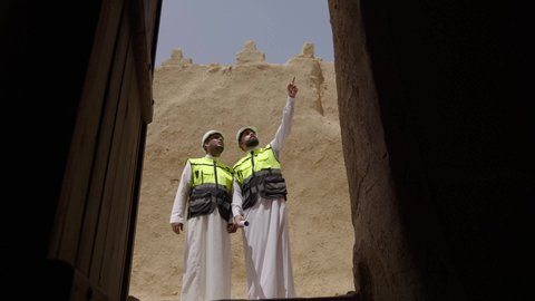 اكتشاف فن العمارة القديم واساسيات بناء البيوت الطينية، مهندسان عربيان خليجيان سعوديان يرتديان السترة وخوذة الحماية يقفان على اطلال قصر سلوى في البجيري الدرعية، يوم بدينا 1727 م، ذكرى تأسيس الدولة السعودية الأولى 22 فبراير