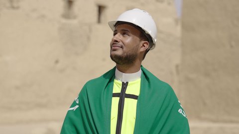 اصول بناء البيوت والقصور التراثية، يوم بدينا 1727 م، اليوم الوطني 23 سبتمبر، التعرف على فن العمارة القديمة، ذكرى تأسيس الدولة السعودية الأولى 22 فبراير، مهندس عربي خليجي سعودي يرتدي السترة والخوذة يحمل شعار الوطن للاحتفال بيوم العلم 11 مارس، التجول في الحي الشعبي