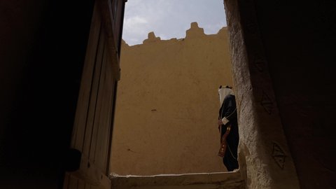 المراقبة والحراسة للدفاع والحفاظ على تاريخ وتراث المملكة، يوم بدينا 22 فبراير، الحرب والقتال بالبنادق لحماية الوطن، تأسيس الدولة السعودية الأولى 1727 م، رجل عربي خليجي سعودي يرتدي الزي الشعبي التقليدي يحمل البندقية في احياء شعبية طينية