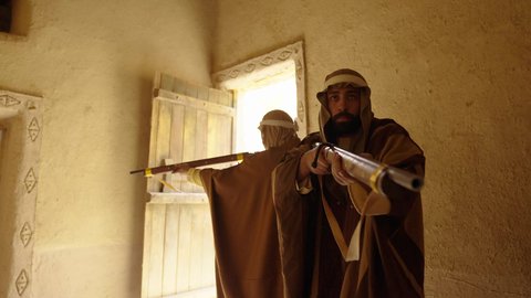 Guarding and monitoring to defend and preserve the history and heritage of the Kingdom, the day we began, February 22, war and fighting with guns to protect the homeland, the establishment of the first Saudi state in 1727 AD, a Saudi Gulf Arab man wearing traditional folk costume carrying a gun in a mud-brick neighborhood