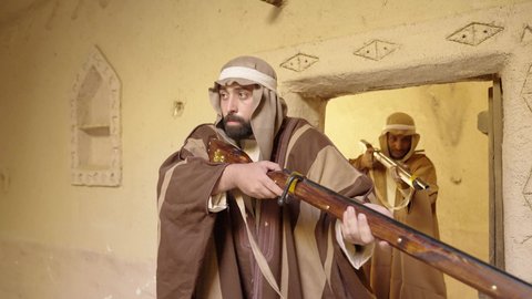 مفهوم المراقبة والحراسة، الدفاع والحفاظ على تاريخ وتراث المملكة، يوم بدينا 22 فبراير، الحرب والقتال بالبنادق لحماية الوطن، تأسيس الدولة السعودية الأولى 1727 م، رجل عربي خليجي سعودي يرتدي الزي الشعبي التقليدي يحمل البندقية في احياء شعبية طينية