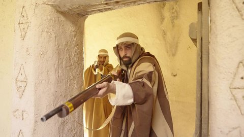 المراقبة والحراسة للدفاع والحفاظ على تاريخ وتراث المملكة، يوم بدينا 22 فبراير، الحرب والقتال بالبنادق لحماية الوطن، تأسيس الدولة السعودية الأولى 1727 م، رجل عربي خليجي سعودي يرتدي الزي الشعبي التقليدي يحمل البندقية في احياء شعبية طينية