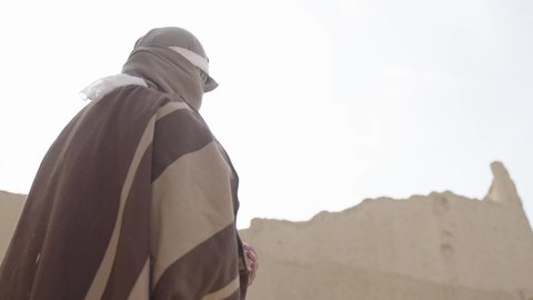 الحفاظ والدفاع على تاريخ وتراث المملكة، يوم بدينا 22 فبراير، الحرب والقتال بالبنادق لحماية الوطن، تأسيس الدولة السعودية الأولى 1727 م، رجل عربي خليجي سعودي يرتدي الزي الشعبي التقليدي يحمل البندقية في احياء شعبية طينية، مفهوم المراقبة والحراسة