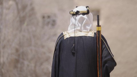 الحراسة والمراقبة للدفاع والحفاظ على تاريخ وتراث المملكة، يوم بدينا 22 فبراير، الحرب والقتال بالبنادق لحماية الوطن، تأسيس الدولة السعودية الأولى 1727 م، رجل عربي خليجي سعودي يرتدي الزي الشعبي التقليدي يحمل البندقية في احياء شعبية طينية
