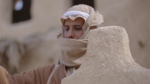 الحرب والقتال بالبنادق لحماية الوطن، تأسيس الدولة السعودية الأولى 1727 م، رجل عربي خليجي سعودي يرتدي الزي الشعبي التقليدي يحمل البندقية في احياء شعبية طينية، مفهوم المراقبة والحراسة، الحفاظ والدفاع على تاريخ وتراث المملكة، يوم بدينا 22 فبراير