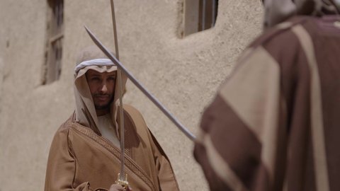 Sword duel for protection and the establishment of the first Saudi state, 1727 AD. Two Saudi Gulf Arab men wearing traditional costumes duel with swords in a mud house. The day we started, February 22. The concept of war and defending the homeland, preserving the history and heritage of the Kingdom, ancient war tools.