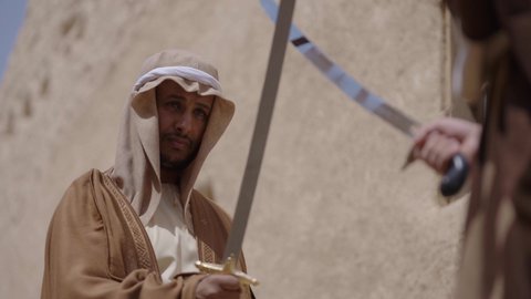 المبارزة بالسيف للحماية وتأسيس الدولة السعودية الأولى 1727 م، رجلان عربيان خليجيان سعوديان يرتديان الزي الشعبي يتبارزان بالسيوف في بيت طيني، يوم بدينا 22 فبراير، مفهوم الحرب والدفاع عن الوطن، الحفاظ على تاريخ وتراث المملكة، أدوات الحرب القديمة