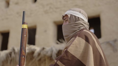 الاستعداد والتجهز للدفاع وحماية الوطن، استخدام السلاح للحفاظ على وممتلكات المملكة، رجل عربي خليجي سعودي يرتدي زي شعبي تقليدي يمسك بيده البندقيه، يوم بدينا  1727 م، ذكرى تأسيس الدولة السعودية الأولى 22 فبراير