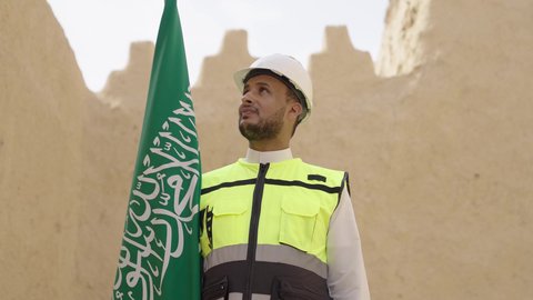 ذكرى تأسيس الدولة السعودية الأولى 22 فبراير، رفع علم المملكة في الأماكن التراثيه الشعبيه في 11 مارس، فن العمارة القديم وبناء البيوت الطينية، مهندس عربي خليجي سعودي مبتسم يرتدي السترة وخوذة الحماية بايماءات الفخر والاعتزاز في اليوم الوطني 23 سبتمبر، يوم بدينا 1727 م