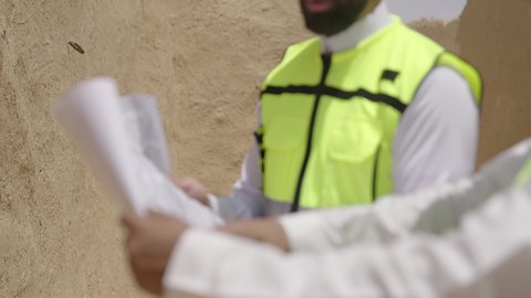 تبادل الاحاديث حول اكتشاف فن العمارة القديم، مهندسان عربيان خليجيان سعوديان يرتديان السترة وخوذة الحماية ينظران الى اساسيات بناء البيوت الطينية، يوم بدينا 1727 م، ذكرى تأسيس الدولة السعودية الأولى 22 فبراير