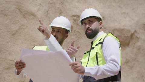 Exchanging conversations about discovering ancient architecture, two Saudi Arabian Gulf engineers wearing jackets and protective helmets look at the basics of building mud houses, the day we began 1727 AD, the anniversary of the founding of the first Saudi state, February 22.