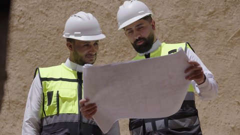 تبادل الاحاديث حول اكتشاف فن العمارة القديم، مهندسان عربيان خليجيان سعوديان يرتديان السترة وخوذة الحماية ينظران الى اساسيات بناء البيوت الطينية، يوم بدينا 1727 م، ذكرى تأسيس الدولة السعودية الأولى 22 فبراير