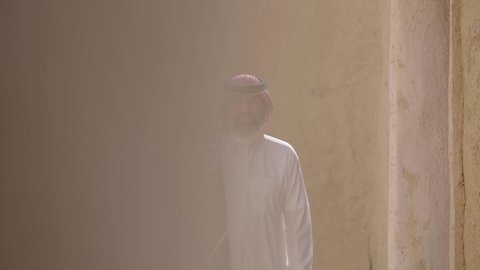 Ancient architecture and mud house construction, Flag Day March 11, Saudi National Day commemoration September 23, gestures of pride and joy in belonging to the homeland, a smiling Saudi Arabian Gulf man wearing a traditional shemagh and thobe standing in a mud house holding the Kingdm's flag, the day we began 1727 AD
