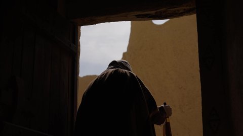 مفهوم حب الوطن والانتماء اليه، قرية تاريخية قديمة، ارتداء الزي الشعبي  التقليدي في عيد ومناسبة وطنية، إحياء ذكرى تأسيس الدولة السعودية الأولى 1727 م, يوم بدينا 22 فبراير, رجل عربي خليجي سعودي يرتدي البشت والغترة والعقال الذهبي العريض يقف أمام منزل طيني قديم