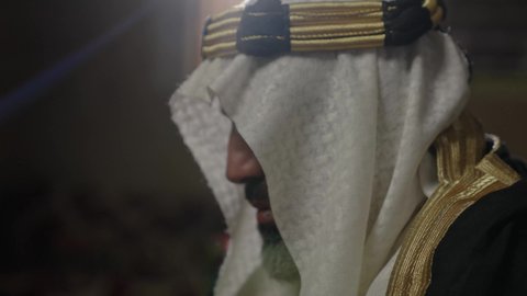 مفهوم حب الوطن والانتماء اليه، قرية تاريخية قديمة، ارتداء الزي الشعبي  التقليدي في عيد ومناسبة وطنية، إحياء ذكرى تأسيس الدولة السعودية الأولى 1727 م, يوم بدينا 22 فبراير, رجل عربي خليجي سعودي يرتدي البشت والغترة والعقال الذهبي العريض يقف أمام منزل طيني قديم