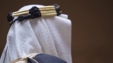 مفهوم حب الوطن والانتماء اليه، قرية تاريخية قديمة، ارتداء الزي الشعبي  التقليدي في عيد ومناسبة وطنية، إحياء ذكرى تأسيس الدولة السعودية الأولى 1727 م, يوم بدينا 22 فبراير, رجل عربي خليجي سعودي يرتدي البشت والغترة والعقال الذهبي العريض يقف أمام منزل طيني قديم