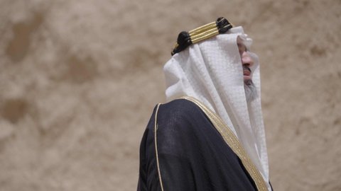 التجول في الاماكن التاريخية القديمة، ذكرى تأسيس الدولة السعودية الأولى 1727 م, يوم بدينا 22 فبراير, رجل عربي خليجي سعودي يرتدي البشت والغترة والعقال الذهبي العريض يقف في مكان أثري قديم، مفهوم حب الوطن والانتماء اليه، ارتداء الزي الشعبي  التقليدي في المناسبة الوطنية