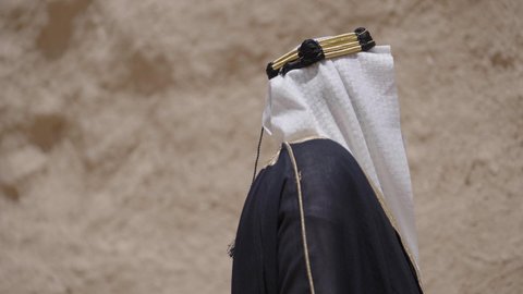التجول في الاماكن التاريخية القديمة، ذكرى تأسيس الدولة السعودية الأولى 1727 م, يوم بدينا 22 فبراير, رجل عربي خليجي سعودي يرتدي البشت والغترة والعقال الذهبي العريض يقف في مكان أثري قديم، مفهوم حب الوطن والانتماء اليه، ارتداء الزي الشعبي  التقليدي في المناسبة الوطنية
