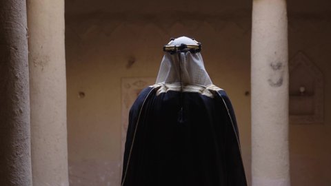 تعابير الفخر والاعتزاز،  قرية تاريخية قديمة، ارتداء الزي الشعبي  التقليدي في عيد ومناسبة وطنية، إحياء ذكرى تأسيس الدولة السعودية الأولى 1727 م, يوم بدينا 22 فبراير, رجل عربي خليجي سعودي يرتدي البشت والغترة والعقال الذهبي العريض يقف في منزل طيني قديم