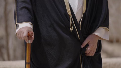 يوم بدينا 22 فبراير, رجل عربي خليجي سعودي يرتدي البشت والغترة والعقال الذهبي العريض يقف في منزل طيني قديم، مفهوم حب الوطن والانتماء اليه، قرية تاريخية قديمة، ارتداء الزي الشعبي  التقليدي في عيد ومناسبة وطنية، إحياء ذكرى تأسيس الدولة السعودية الأولى 1727 م