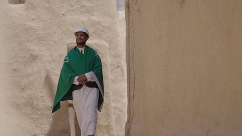 مهندس عربي خليجي سعودي مبتسم يرتدي السترة وخوذة الحماية بايماءات الفخر والاعتزاز في اليوم الوطني 23 سبتمبر، يوم بدينا 1727 م، ذكرى تأسيس الدولة السعودية الأولى 22 فبراير، رفع علم المملكة في الأماكن التراثيه الشعبيه في 11 مارس، فن العمارة القديم وبناء البيوت الطينية