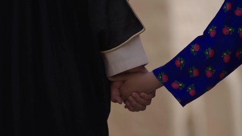 بيت طيني في قرية أثرية قديمة، ذكرى تأسيس الدولة السعودية الأولى1727 م، يوم بدينا22 فبراير، تصوير مقرب لرجل عربي خليجي سعودي يرتدي البشت والغترة يمسك بيد ابنته ويتجولان في الحي التاريخي المبني على الطراز القديم