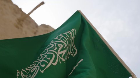 The flag of the Kingdom of Saudi Arabia waving in an ancient historical place, celebrating Saudi National Day on September 23, Flag Day on March 11, the banner of monotheism and Islam in an old clay house, national celebrations and occasions, the concept of love and belonging to the homeland