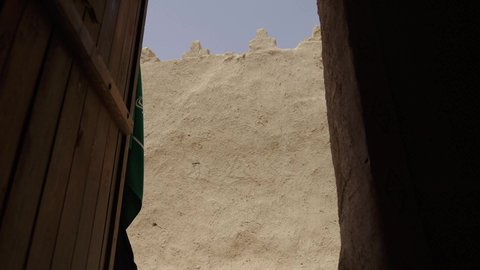 الاحتفال باليوم الوطني 23 سبتمبر, ذكرى يوم التأسيس 22 فبراير, سيدة عربية خليجية سعودية ترتدي العباءة السوداء والبرقع تمسك بيدها العلم وتتجول في الاحياء القديمة, يوم العلم السعودي 11 مارس, التفاخر بالإنتماء للوطن, ارتداء الأزياء الشعبية التقليدية في المناسبة الوطنية