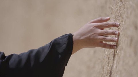 ذكرى تأسيس الدولة السعودية الاولى 22 فبراير، تصوير مقرب ليد امرأة عربية خليجية سعودية ترتدي الزي الشعبي تقوم بلمس جدار من الطين، البيوت الطينية التراثية في المملكة العربية السعودية، الاعتزاز والفخر بالتاريخ، يوم بدينا 1727 م