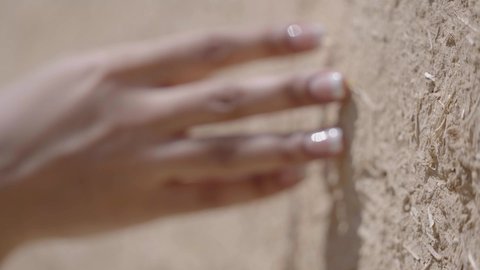 يوم بدينا 1727 م، ذكرى تأسيس الدولة السعودية الاولى 22 فبراير، تصوير مقرب ليد امرأة عربية خليجية سعودية ترتدي الزي الشعبي تقوم بلمس جدار من الطين، البيوت الطينية التراثية في المملكة العربية السعودية، الاعتزاز والفخر بالتاريخ