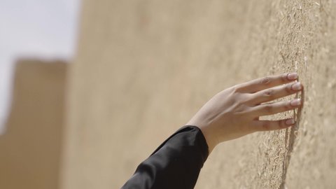 ذكرى تأسيس الدولة السعودية الاولى 22 فبراير، تصوير مقرب ليد امرأة عربية خليجية سعودية ترتدي الزي الشعبي تقوم بلمس جدار من الطين، البيوت الطينية التراثية في المملكة العربية السعودية، الاعتزاز والفخر بالتاريخ، يوم بدينا 1727 م