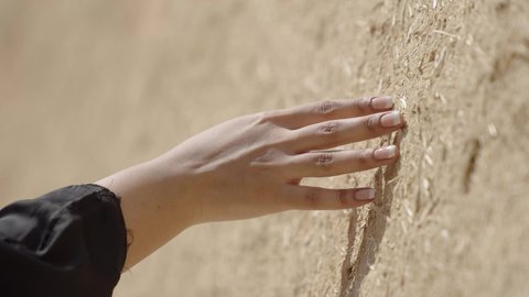 ذكرى تأسيس الدولة السعودية الاولى 22 فبراير، تصوير مقرب ليد امرأة عربية خليجية سعودية ترتدي الزي الشعبي تقوم بلمس جدار من الطين، البيوت الطينية التراثية في المملكة العربية السعودية، الاعتزاز والفخر بالتاريخ، يوم بدينا 1727 م