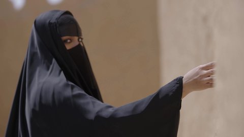 إظهار الجمال العربي البدوي للنساء السعوديات، يوم بدينا 1727 م، ارتداء الزي الشعبي في ذكرى تأسيس الدولة السعودية الاولى 22 فبراير، تصوير مقرب لامرأة عربية خليجية سعودية ترتدي العباءة السوداء والبرقع تتجول في منزل طيني شعبي