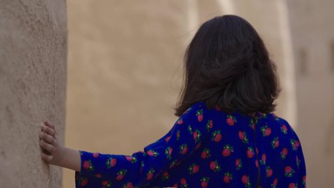 المحافظة على التراث السعودي، تربيه الأبناء على حب الوطن، يوم بدينا 1727 م، ذكرى تأسيس الدولة السعودية الاولى 22 فبراير، تصوير مقرب لفتاة عربيه خليجية سعودية مبتسمة ترتدي الزي التقليدي الشعبي تتجول في منزل طيني، الاحتفال بالمناسبات والأعياد الوطنية بإيماءات السعادة