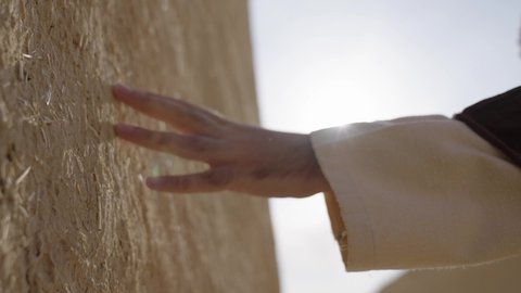 Traditional mud houses, the day we started 1727 AD, commemorating the founding of the first Saudi state, February 22, a close-up of the hand of a Saudi Gulf Arab man wearing traditional clothing touching a mud wall