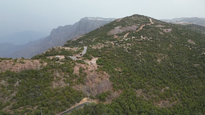 سلاسل جبال أبها والنماص الصخرية، التضاريس الحجرية الوعرة، تصوير جوي للبيئة الجبلية في منطقة عسير، جذب واستقطاب السياح من كافة انحاء العالم، الأماكن والمعالم السياحية الطبيعية المشهورة، الأشجار والنباتات على سفوح الجبل