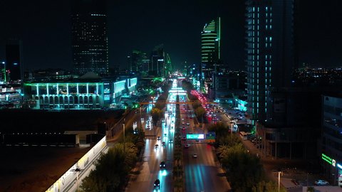 Transportation and traffic movement on the main streets and roads in the Kingdom of Saudi Arabia, aerial drone footage of organized traffic in the capital, the growth and development of infrastructure, and towers lit up in green to celebrate Saudi National Day in Riyadh.