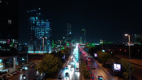 Transportation and traffic movement on the main streets and roads in the Kingdom of Saudi Arabia, aerial drone footage of organized traffic in the capital, the growth and development of infrastructure, and towers lit up in green to celebrate Saudi National Day in Riyadh.