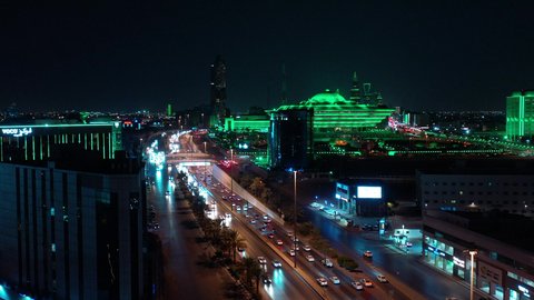 Transportation and traffic movement on the main streets and roads in the Kingdom of Saudi Arabia, aerial drone footage of organized traffic in the capital, the growth and development of infrastructure, and towers lit up in green to celebrate Saudi National Day in Riyadh.