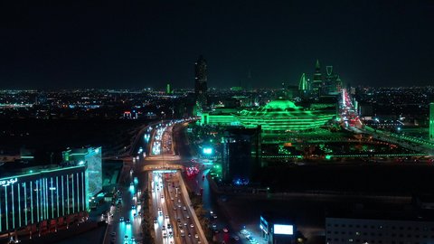  حركة وسائل النقل والمواصلات في الشوارع والطرقات الرئيسية في المملكة العربية السعودية، تصوير درون جوي للحركة المرورية المنظمة للسيارات في العاصمة، نمو وتطور البنية التحتية، ابراج مضاءة باللون الاخضر للاحتفال باليوم الوطني السعودي  في الرياض