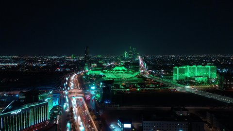 Transportation and traffic movement on the main streets and roads in the Kingdom of Saudi Arabia, aerial drone footage of organized traffic in the capital, the growth and development of infrastructure, and towers lit up in green to celebrate Saudi National Day in Riyadh.